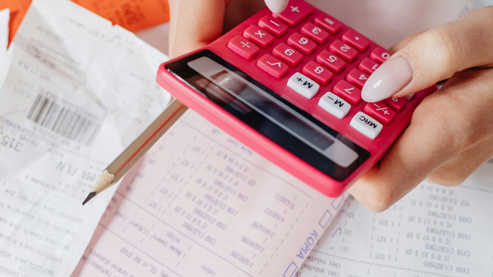 Person reviewing monthly budget with calculator and notebook
