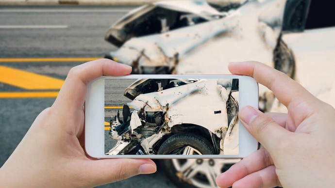 Close-up of someone taking pictures of vehicle damage after a car crash