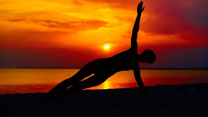 Woman stretching at sunrise feeling energized and positive