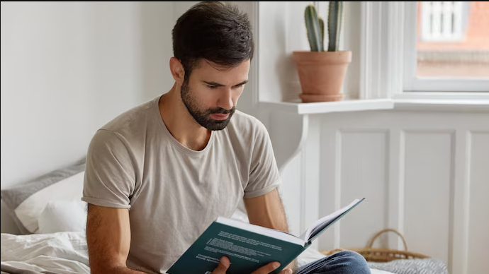 Man reading a book to relax before bedtime